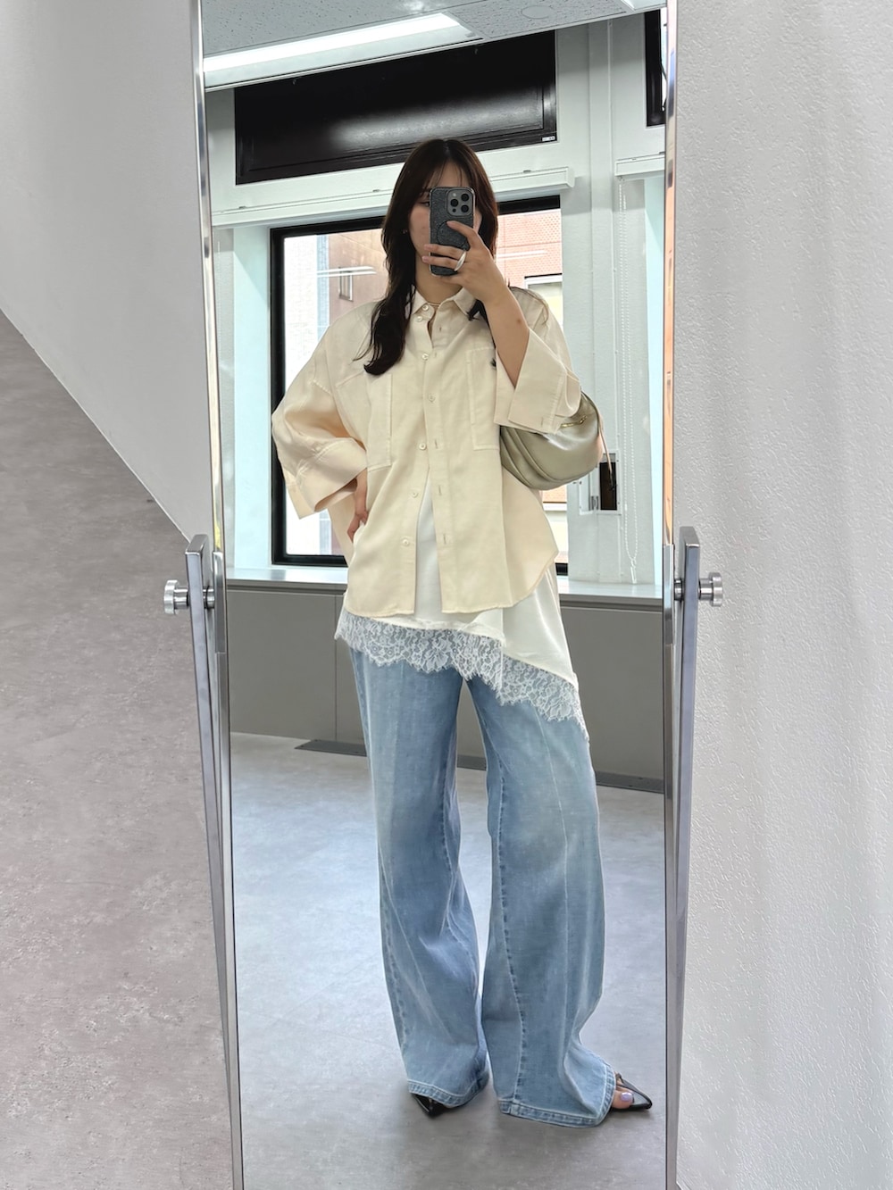 ブルー系のデニムパンツ、ホワイト系のキャミソール、ゴールド系のショルダーバッグを着用したレディースの春コーディネートの3枚目の写真