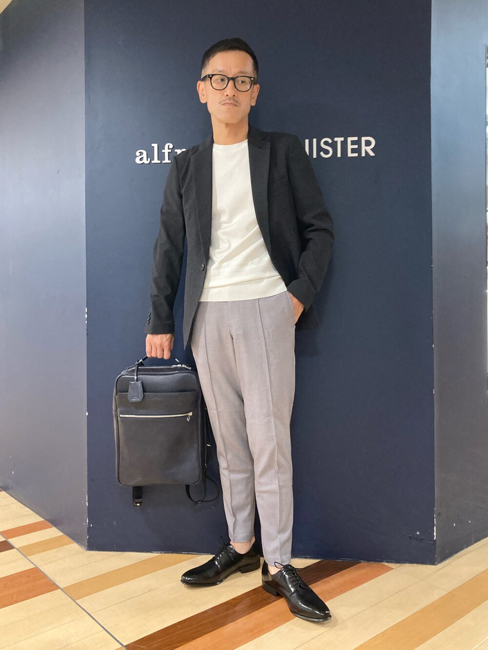 ブルー系のバックパック/リュック、グレー系のテーラードジャケット、ホワイト系のTシャツ/カットソーを着用したメンズの春コーディネートの3枚目の写真