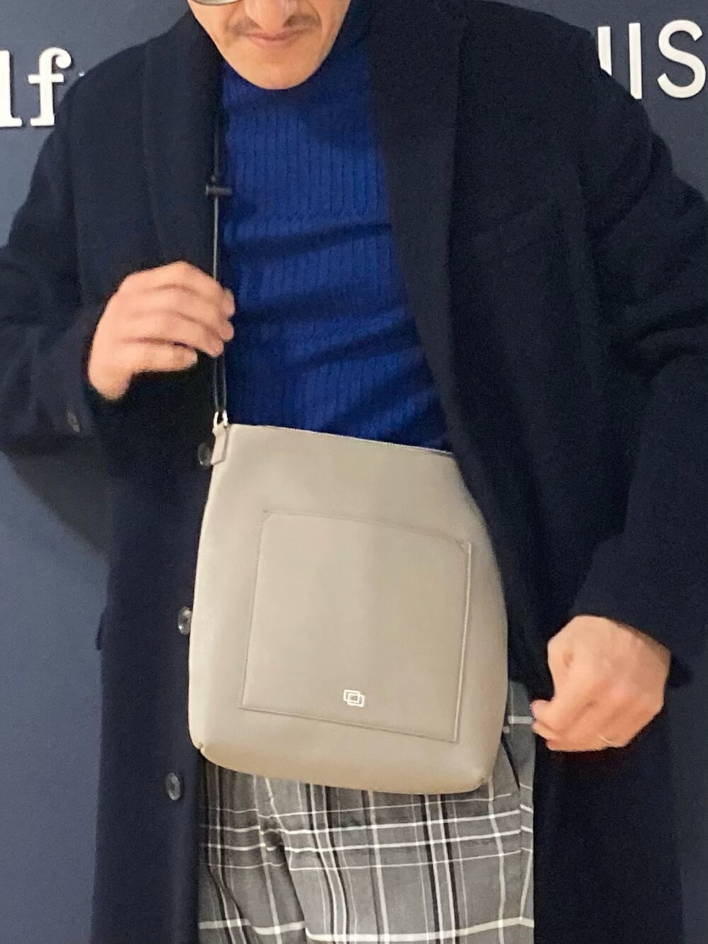 グレー系のショルダーバッグ、ブルー系のニット/セーター、ブルー系のチェスターコートを着用したメンズの冬コーディネートの2枚目の写真