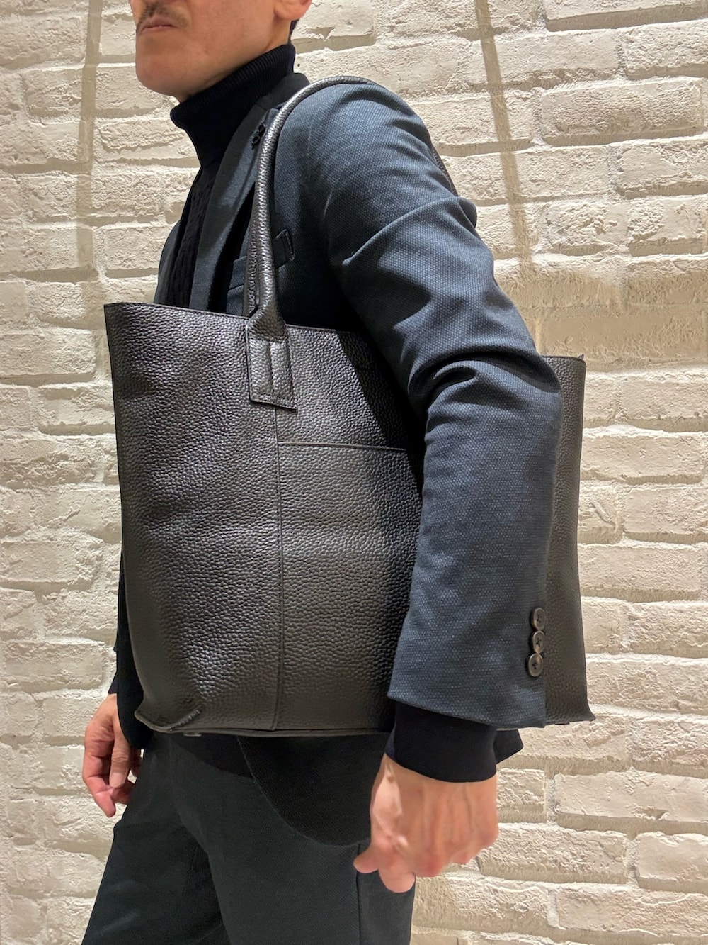 ブラック系のトートバッグを着用したメンズの冬コーディネートの2枚目の写真