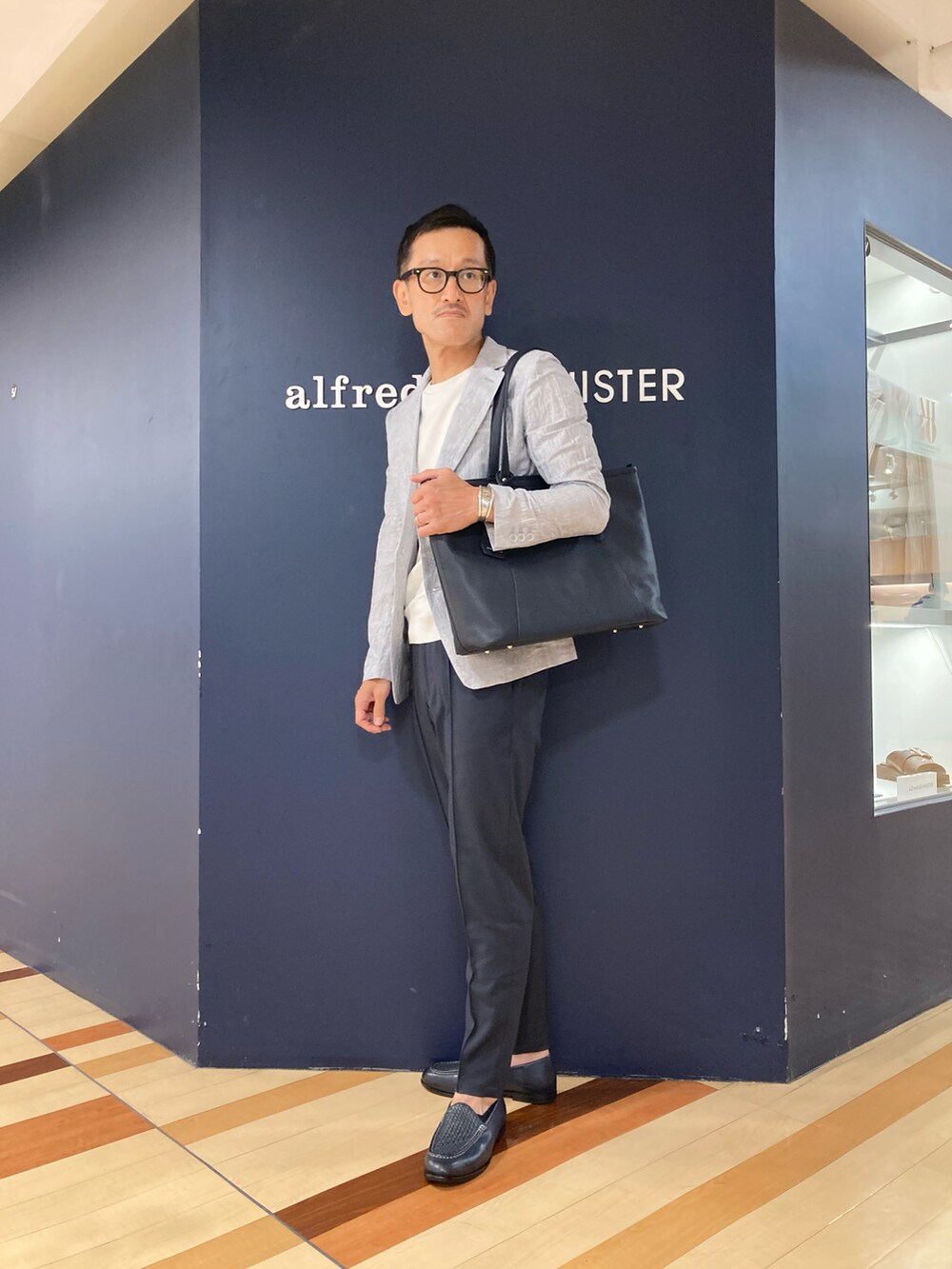 ブルー系のスリッポン、ブルー系のトートバッグ、ホワイト系のテーラードジャケットを着用したメンズの春コーディネートの2枚目の写真