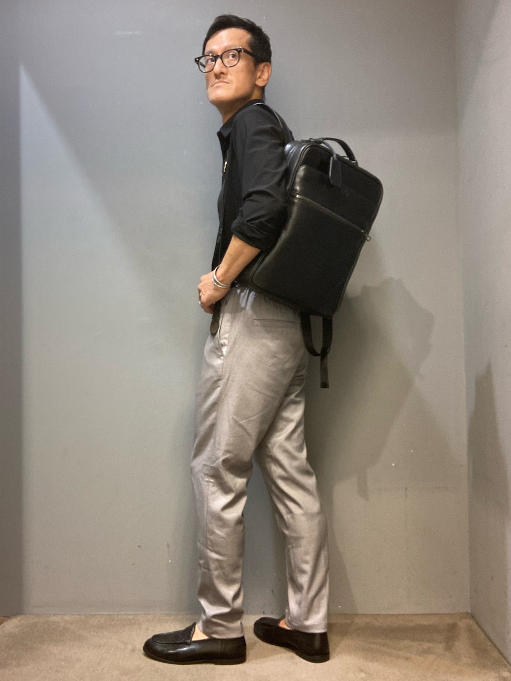 ブラック系のシャツ/ブラウス、グレー系のその他パンツ、ブラック系のバックパック/リュックを着用したメンズの夏コーディネートの3枚目の写真