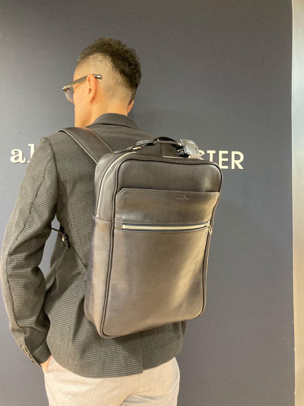 ブルー系のバックパック/リュック、グレー系のテーラードジャケット、ホワイト系のTシャツ/カットソーを着用したメンズの春コーディネートの2枚目の写真