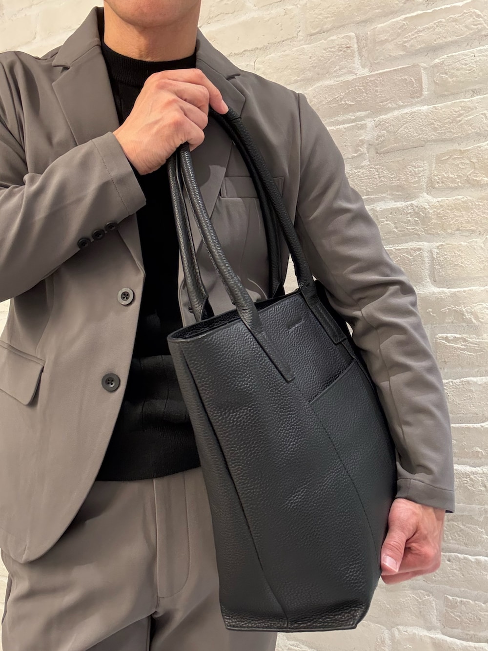 ブラック系のトートバッグ、ブラック系のローファーを着用したメンズの冬コーディネートの3枚目の写真