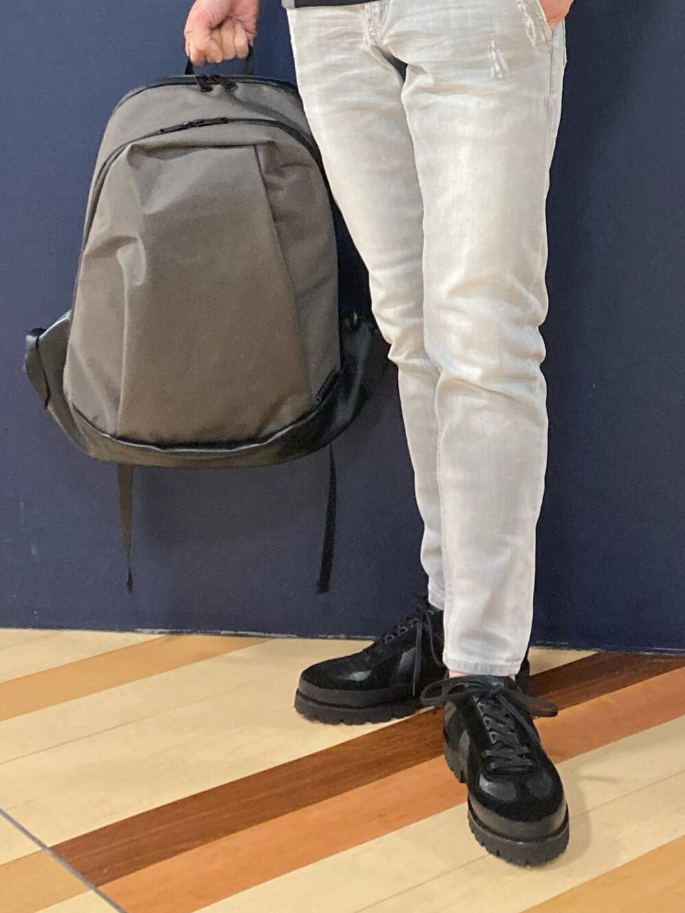 ブラック系のTシャツ/カットソー、グレー系のデニムパンツ、グレー系のバックパック/リュックを着用したメンズの春コーディネートの2枚目の写真