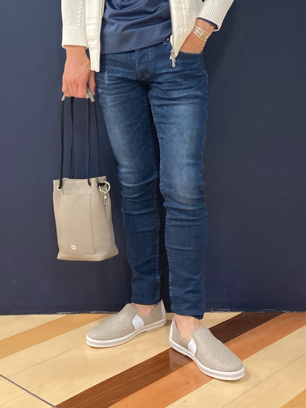 グレー系のスリッポン、グレー系のトートバッグ、ブルー系のデニムパンツを着用したメンズの春コーディネートの2枚目の写真