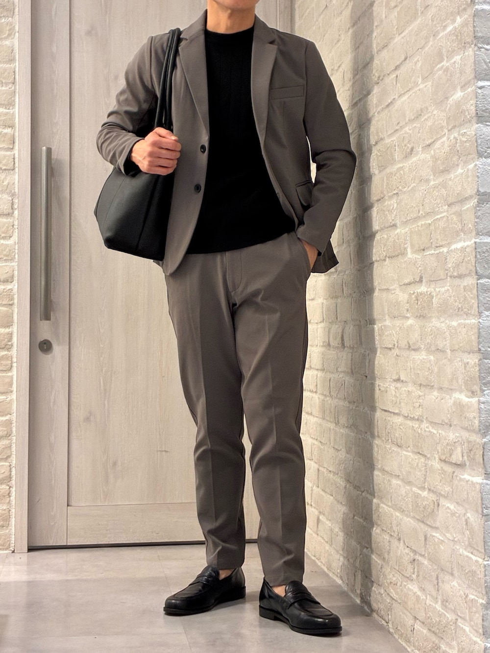 ブラック系のトートバッグ、ブラック系のローファーを着用したメンズの冬コーディネートの2枚目の写真