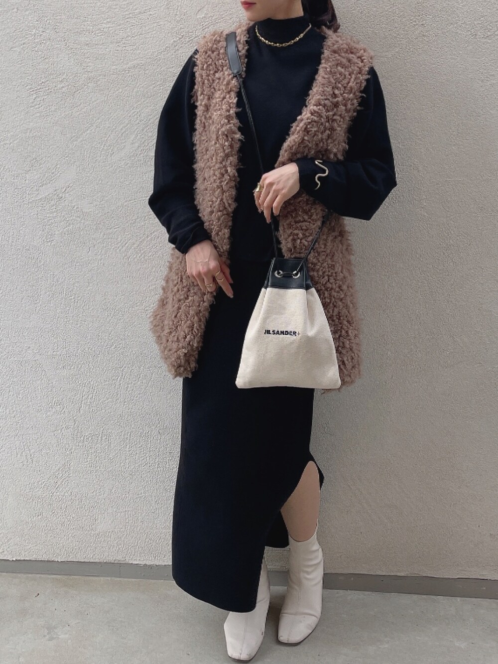 ホワイト系のブーツ、ホワイト系のショルダーバッグ、ベージュ系のベストを着用したレディースの冬コーディネートの3枚目の写真