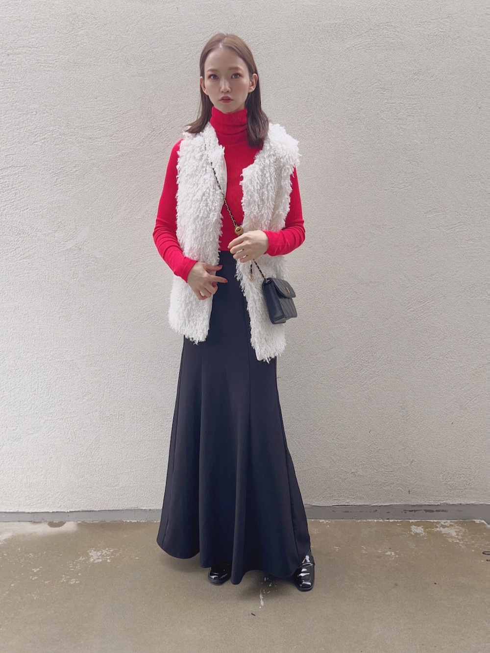 ブラック系のスカート、ホワイト系のベストを着用したレディースの秋コーディネートの2枚目の写真