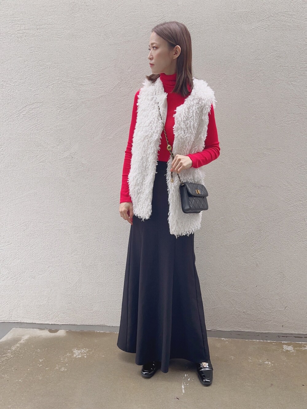 ブラック系のスカート、ホワイト系のベストを着用したレディースの秋コーディネートの3枚目の写真