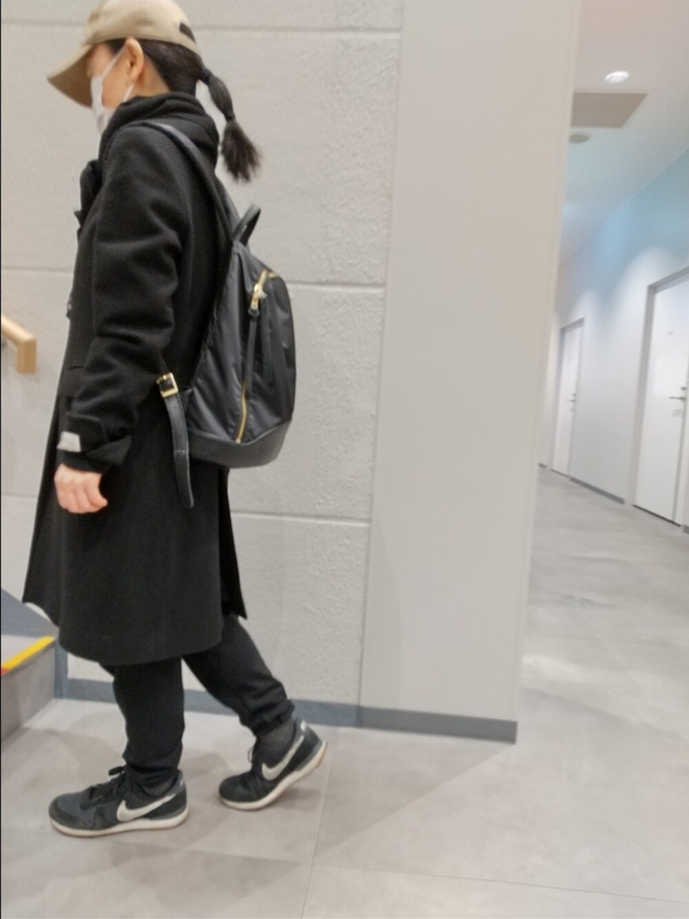 ブラック系のチェスターコート、ブラック系のパンツ、ブラック系のスニーカーを着用したレディースの冬コーディネートの4枚目の写真
