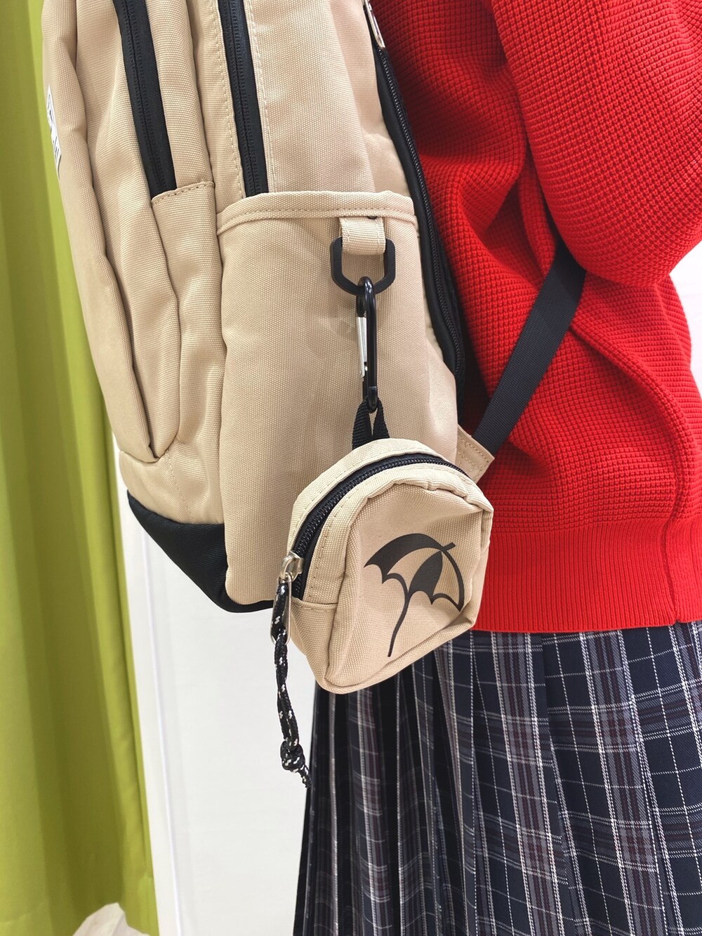 レッド系のニット/セーター、ブラック系のスカート、ベージュ系のバックパック/リュックを着用したレディースの秋コーディネートの3枚目の写真