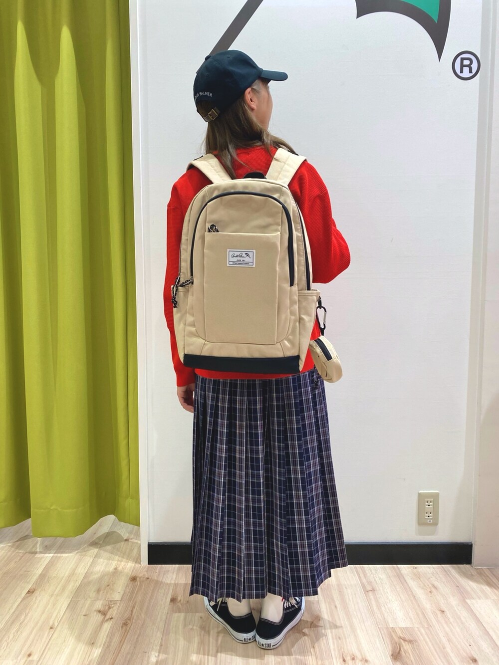 レッド系のニット/セーター、ブラック系のスカート、ベージュ系のバックパック/リュックを着用したレディースの秋コーディネートの2枚目の写真