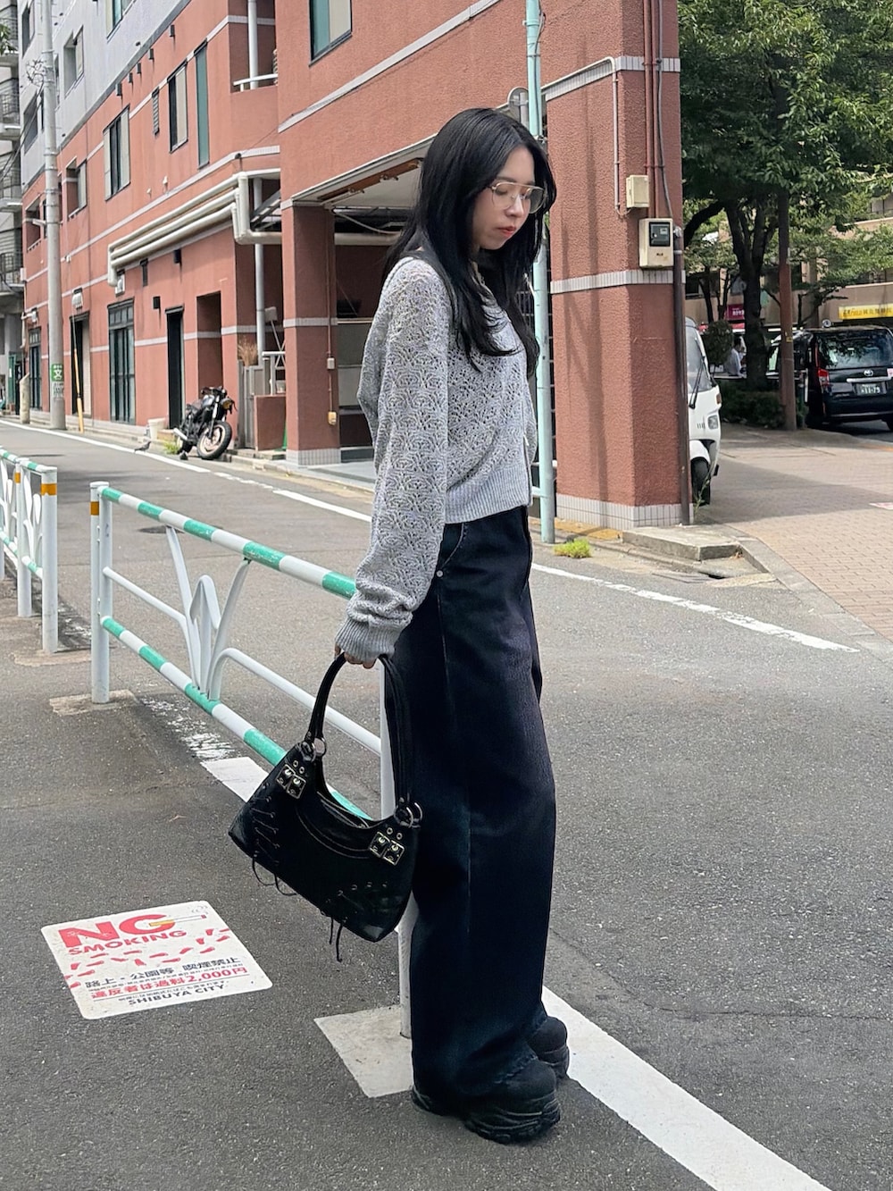 グレー系のニット/セーター、ブラック系のショルダーバッグ、ブルー系のデニムパンツを着用したレディースの夏コーディネートの2枚目の写真