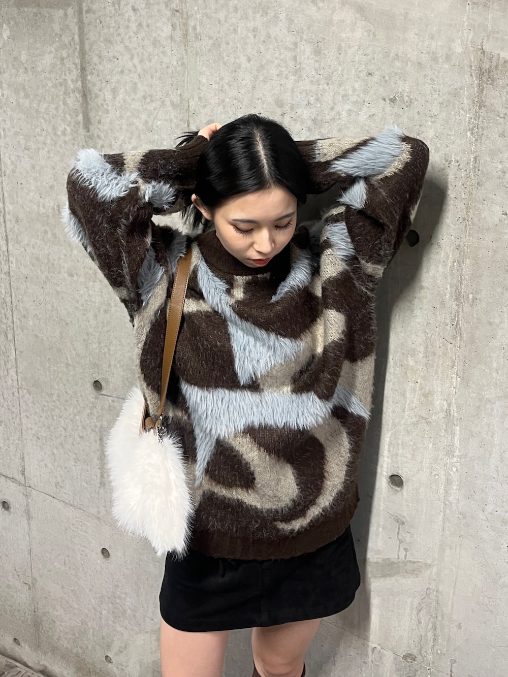 ブラウン系のニット/セーター、ブラウン系のブーツ、ホワイト系のショルダーバッグを着用したレディースの秋コーディネートの5枚目の写真