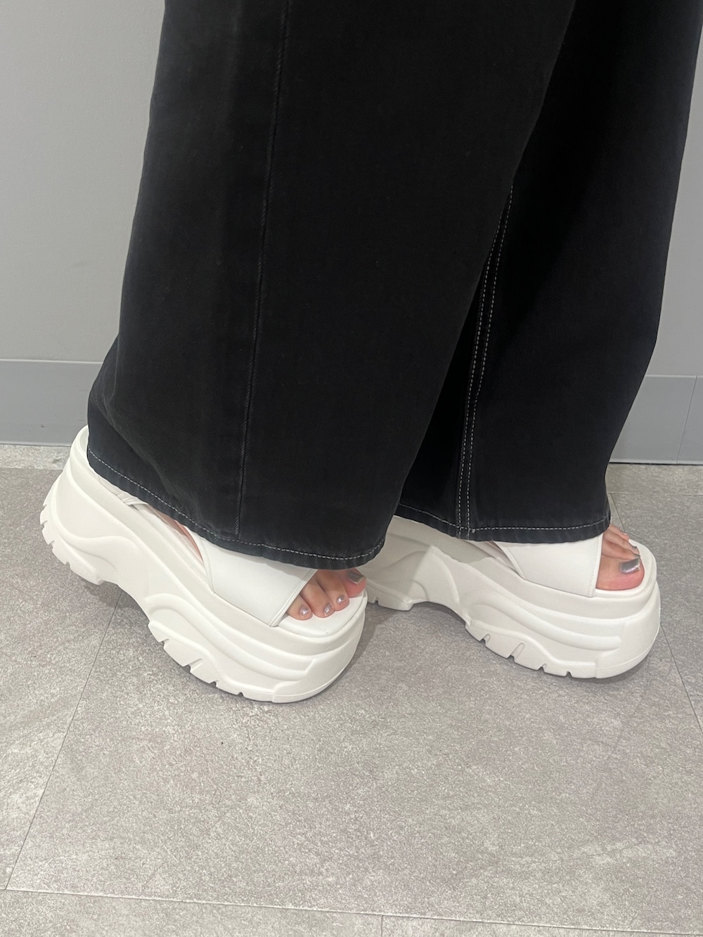 ブラック系のデニムパンツ、グレー系のTシャツ/カットソー、ホワイト系のサンダルを着用したレディースの夏コーディネートの9枚目の写真