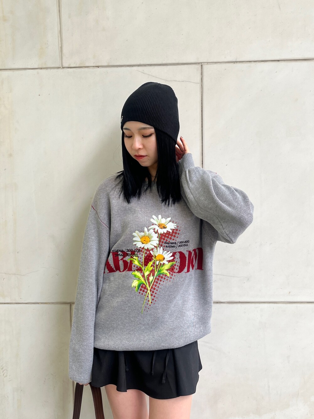 グレー系のニット/セーター、ブラック系のスカート、ブラウン系のショルダーバッグを着用したレディースの春コーディネートの4枚目の写真