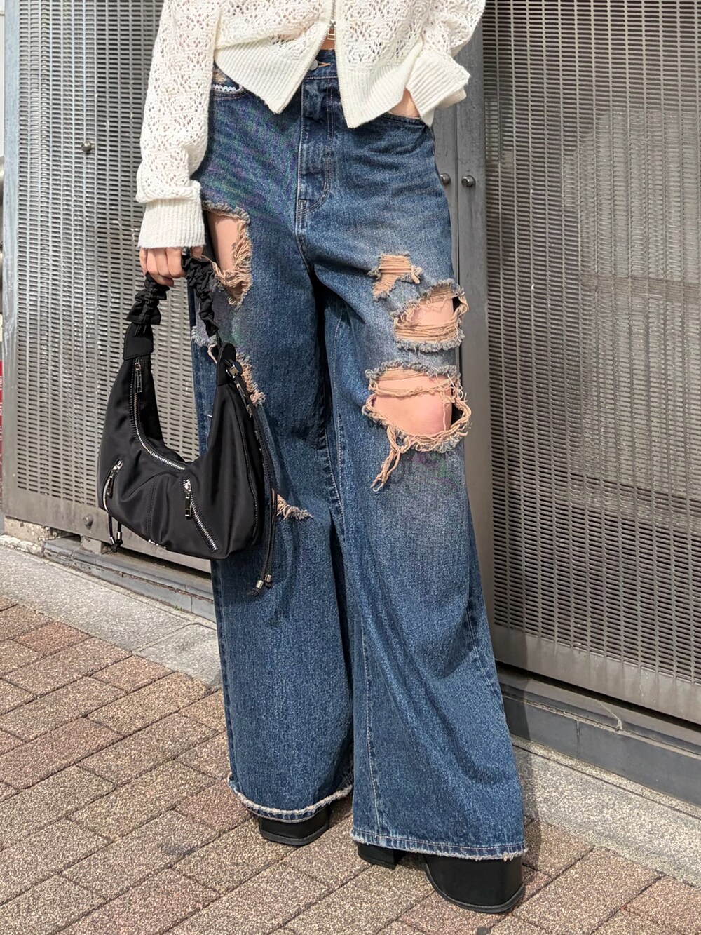 ホワイト系のパーカー、ブルー系のデニムパンツ、ブラック系のサンダルを着用したレディースの春コーディネートの5枚目の写真