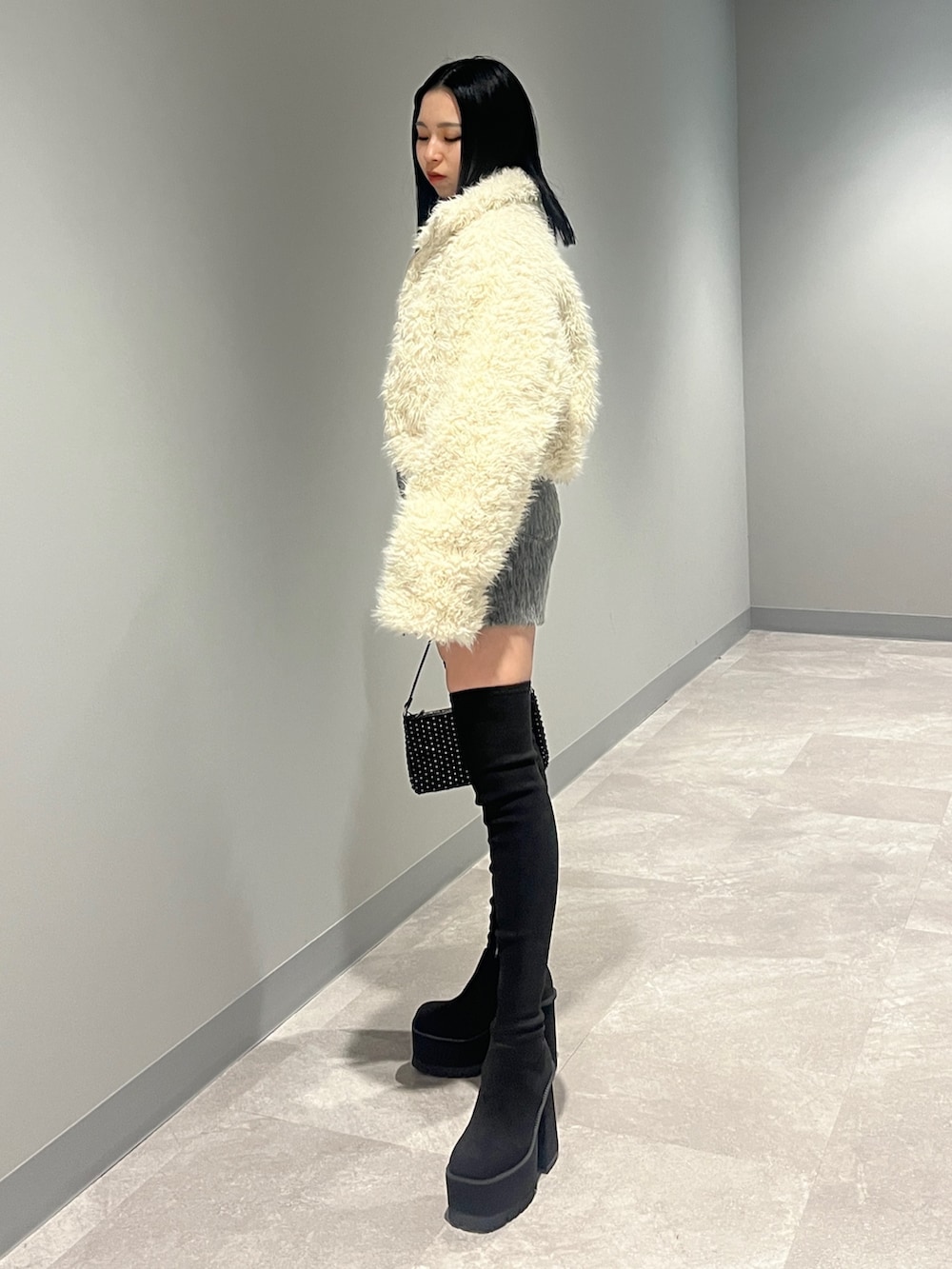 ホワイト系のブルゾン、ブラック系のカーディガン/ボレロ、グレー系のその他パンツを着用したレディースの冬コーディネートの2枚目の写真