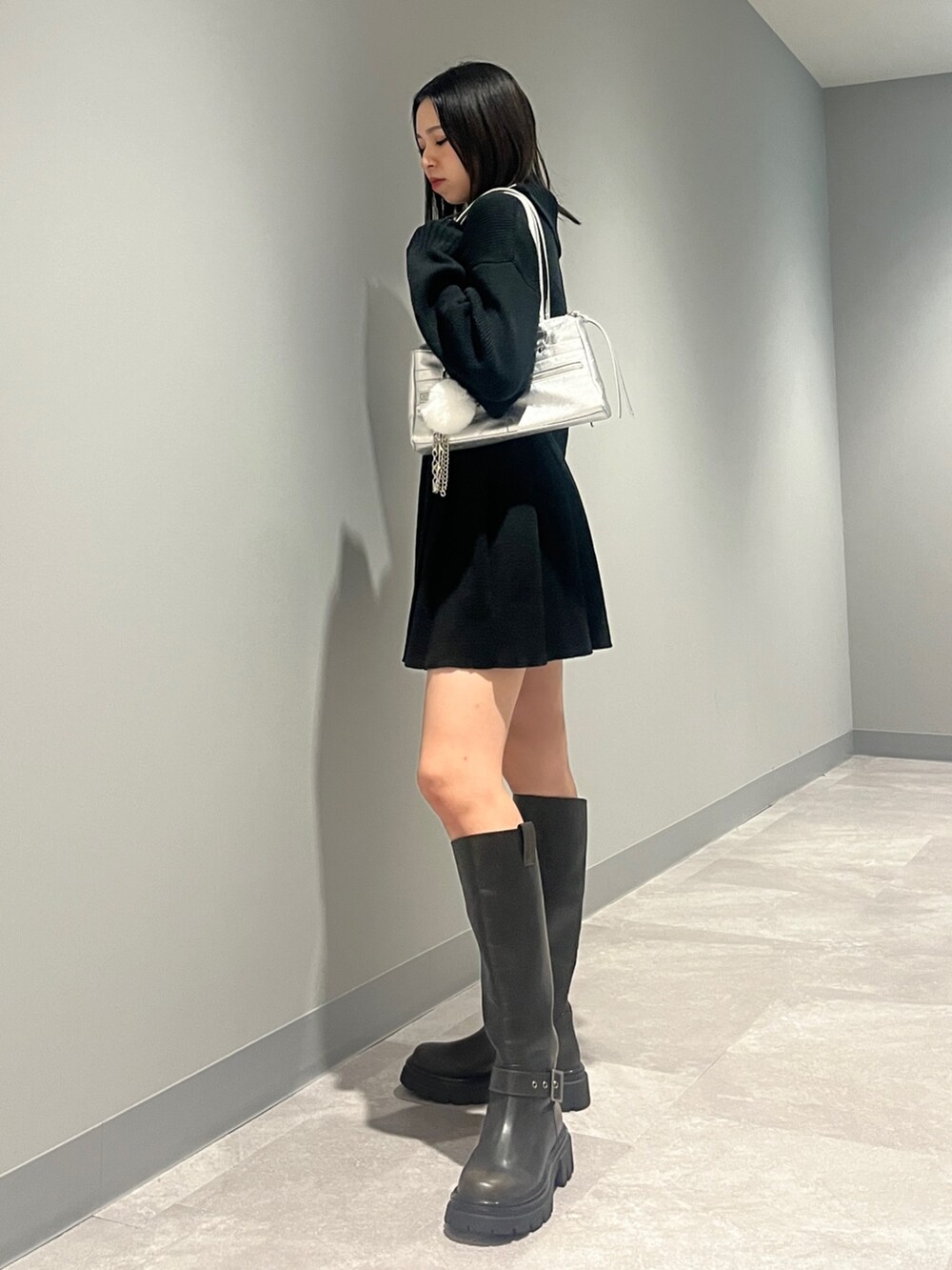 ブラック系のニット/セーター、ブラック系のスカート、ブラック系のブーツを着用したレディースの秋コーディネートの2枚目の写真