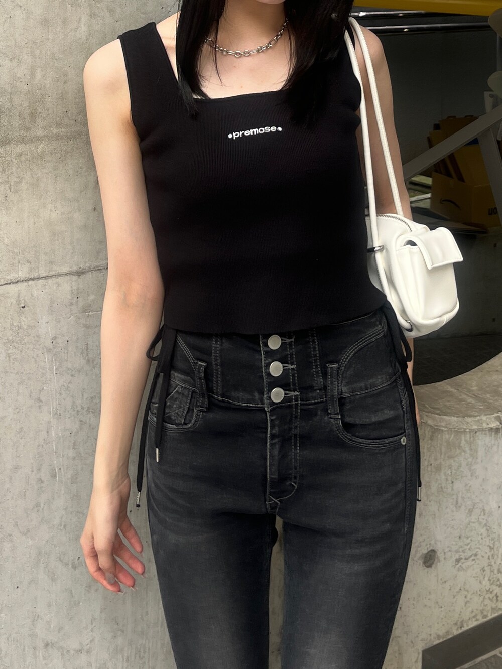 ブラック系のデニムパンツ、ブラック系のサンダル、ホワイト系のハンドバッグを着用したレディースの夏コーディネートの4枚目の写真