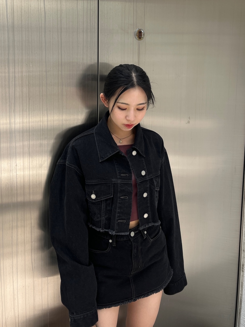 ブラック系のデニムジャケット、ブラック系のスカート、レッド系のTシャツ/カットソーを着用したレディースの夏コーディネートの3枚目の写真