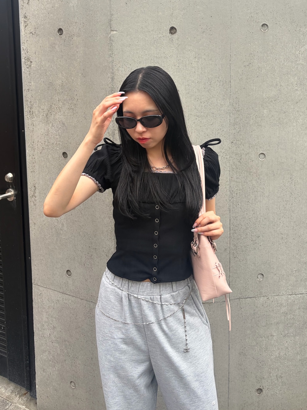 グレー系のスウェットパンツ、ブラック系のTシャツ/カットソー、ピンク系のショルダーバッグを着用したレディースの夏コーディネートの4枚目の写真