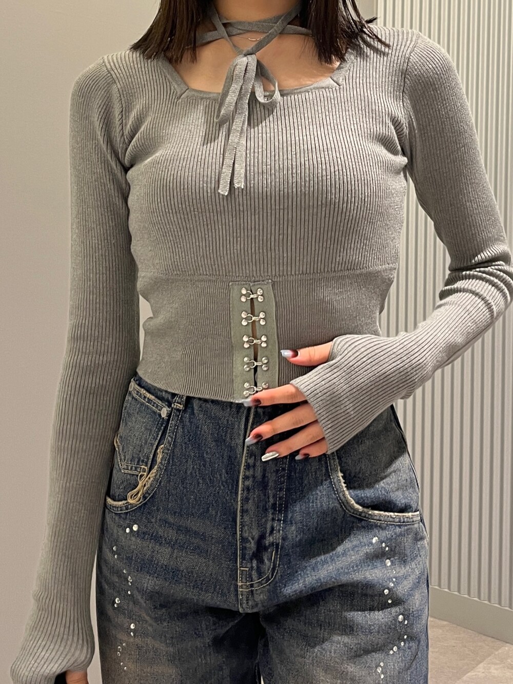 グレー系のニット/セーター、ブルー系のデニムパンツ、ブラック系のショルダーバッグを着用したレディースの秋コーディネートの4枚目の写真