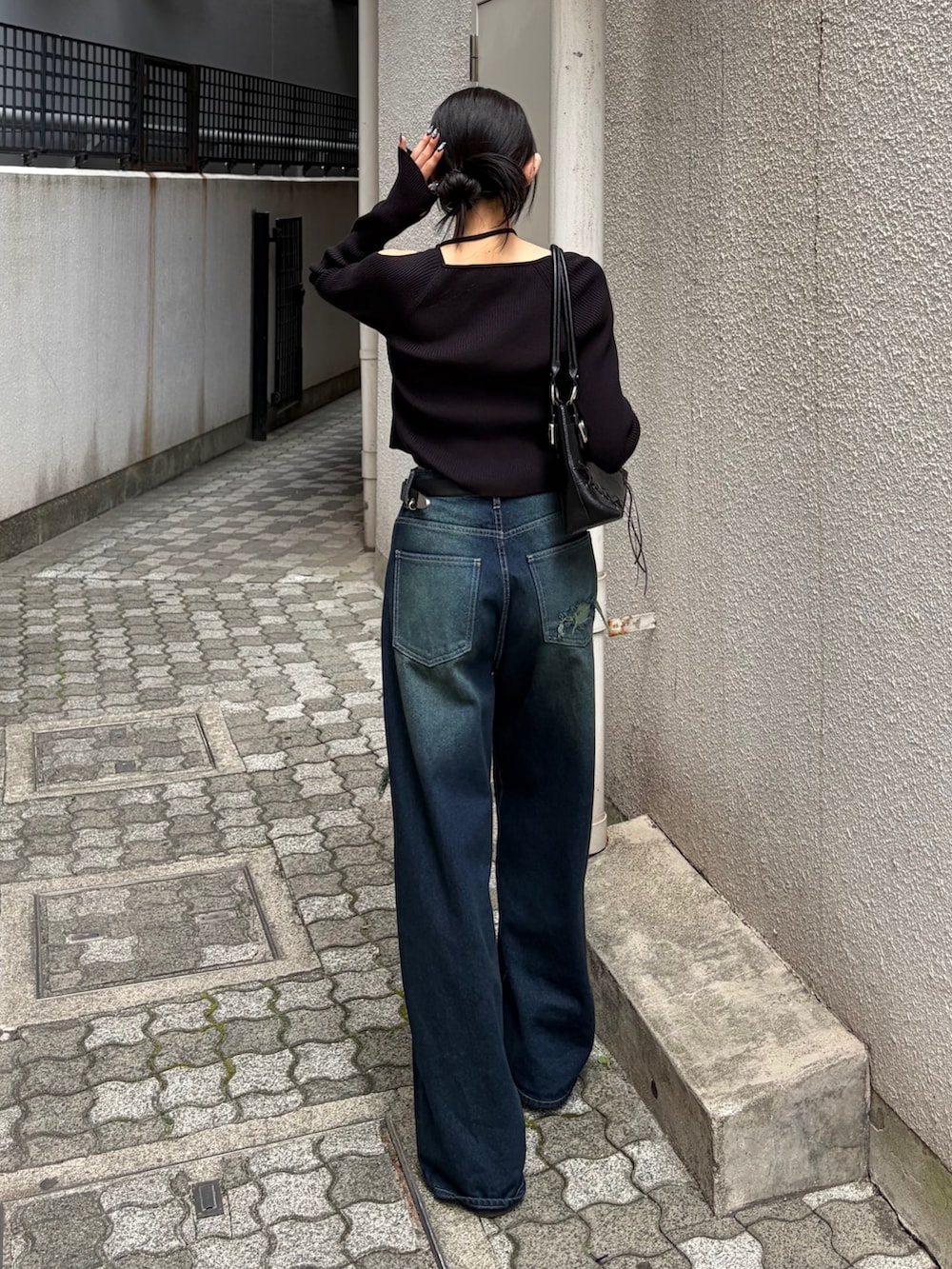 ブラック系のニット/セーター、ブルー系のデニムパンツ、ブラック系のショルダーバッグを着用したレディースの秋コーディネートの3枚目の写真