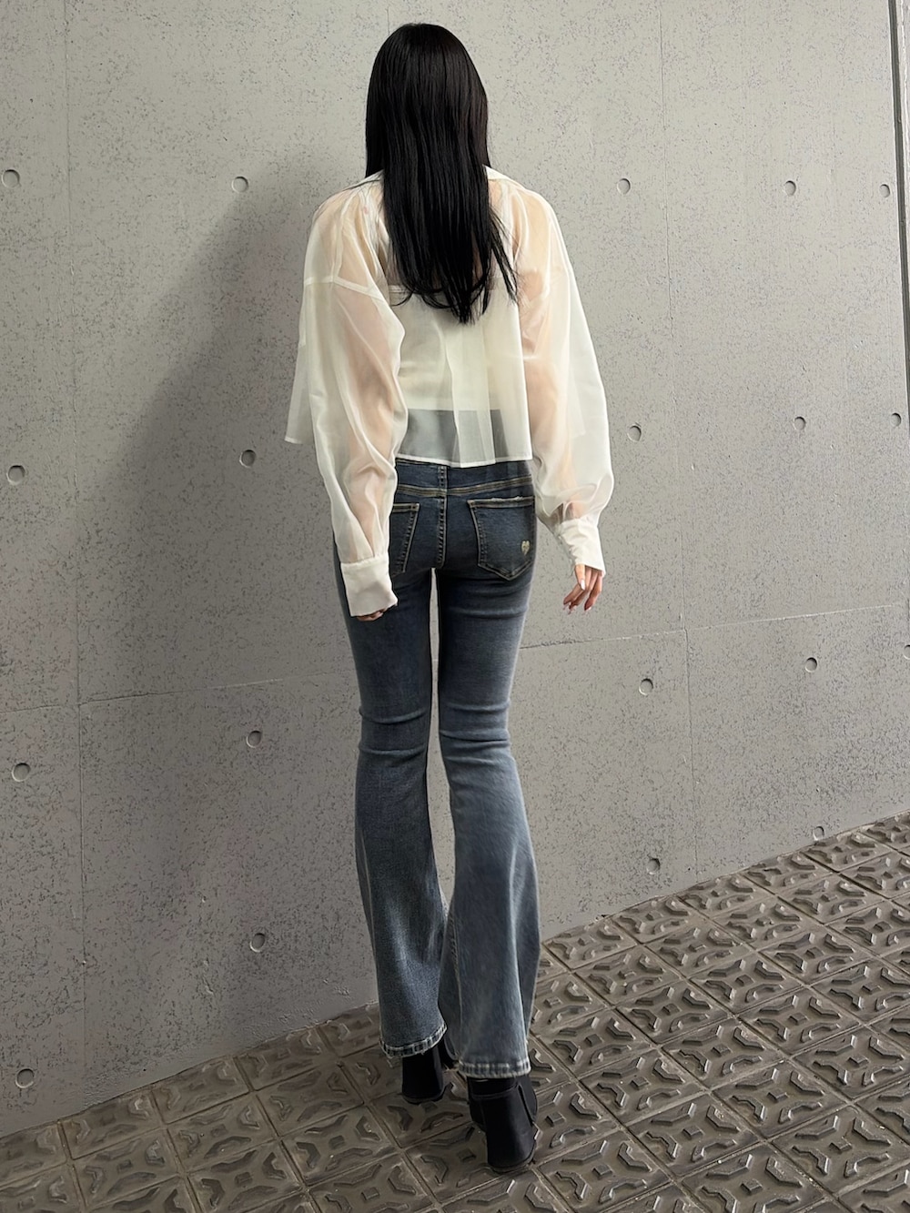 ブルー系のデニムパンツ、ブラック系のサンダル、ホワイト系のキャミソールを着用したレディースの春コーディネートの3枚目の写真