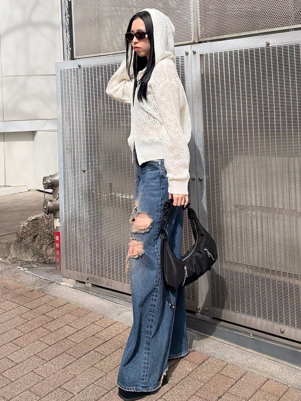ホワイト系のパーカー、ブルー系のデニムパンツ、ブラック系のサンダルを着用したレディースの春コーディネートの2枚目の写真
