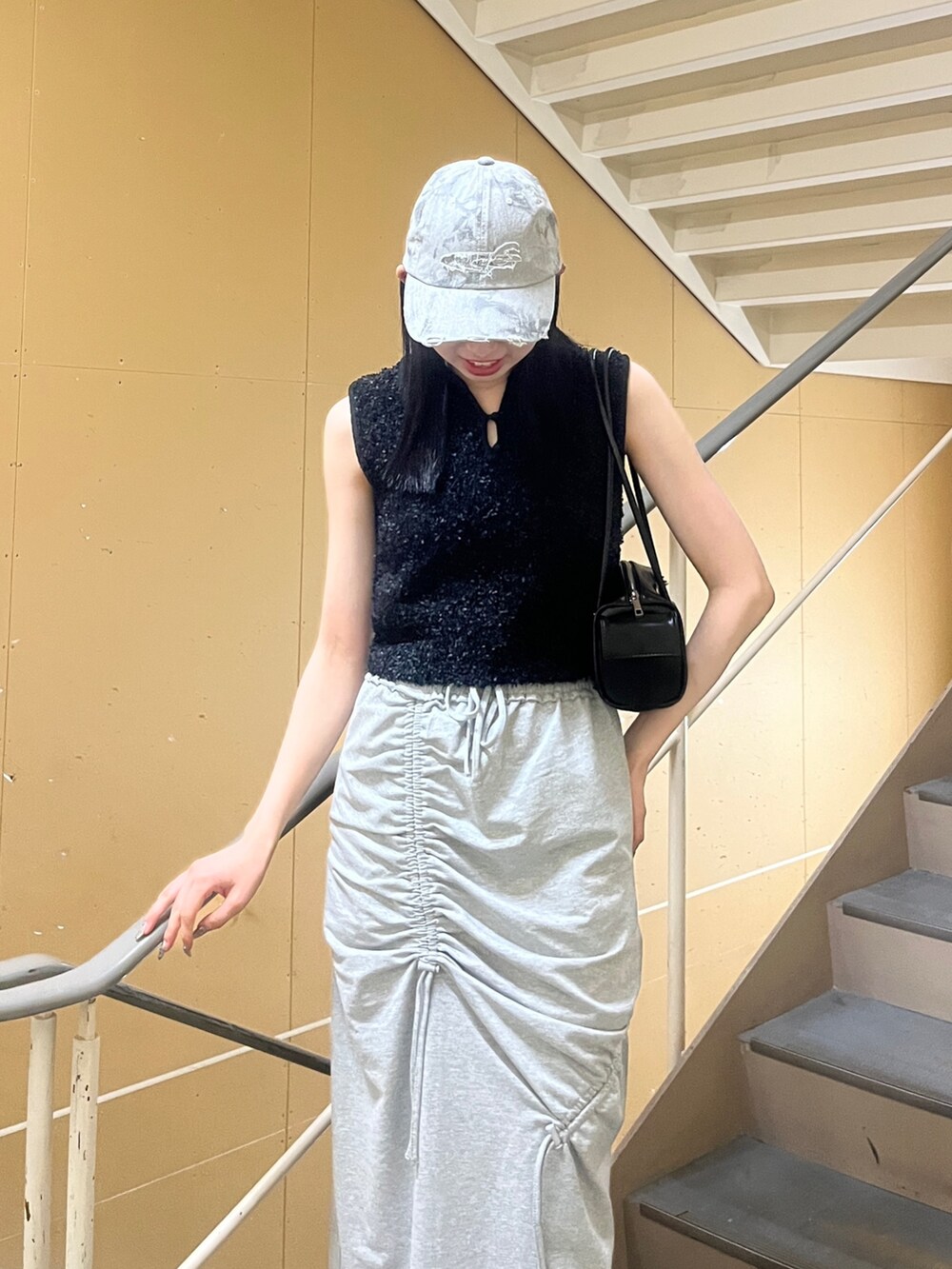 ブラック系のニット/セーター、グレー系のスカート、ブラック系のサンダルを着用したレディースの夏コーディネートの4枚目の写真
