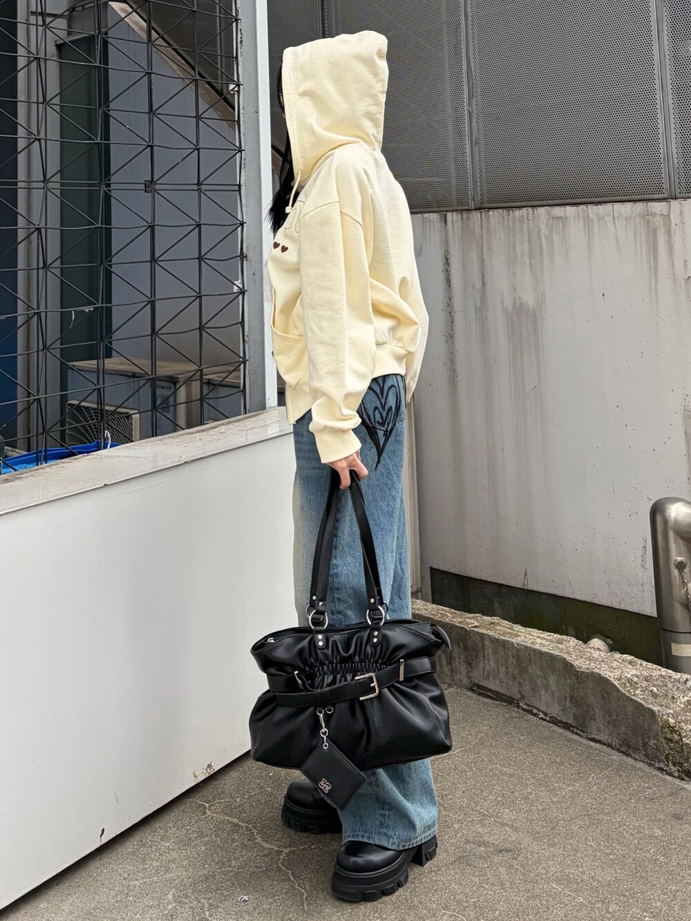 ホワイト系のパーカー、ブルー系のデニムパンツ、ブラック系のトートバッグを着用したレディースの冬コーディネートの3枚目の写真