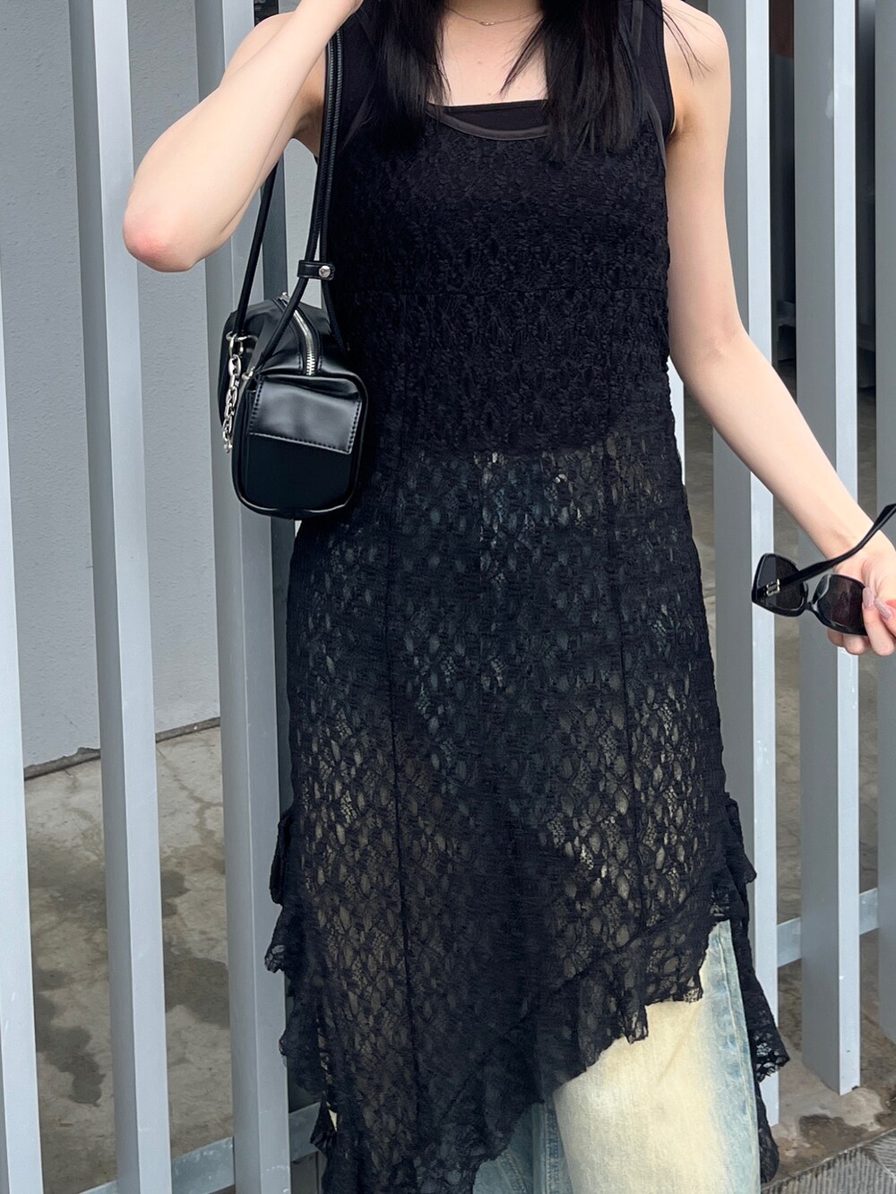 ブラック系のワンピース、ブルー系のデニムパンツ、ブラック系のサンダルを着用したレディースの夏コーディネートの4枚目の写真