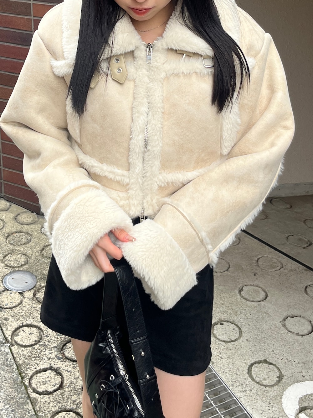 ブラック系のブーツ、ホワイト系のブルゾン、ブラック系のスカートを着用したレディースの冬コーディネートの3枚目の写真