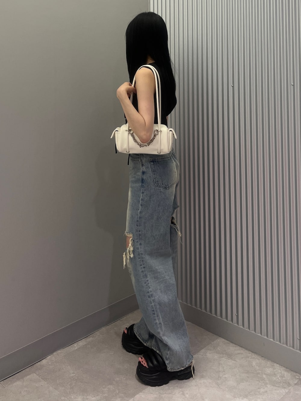 ブルー系のデニムパンツ、ホワイト系のハンドバッグ、ブラック系のTシャツ/カットソーを着用したレディースの夏コーディネートの2枚目の写真