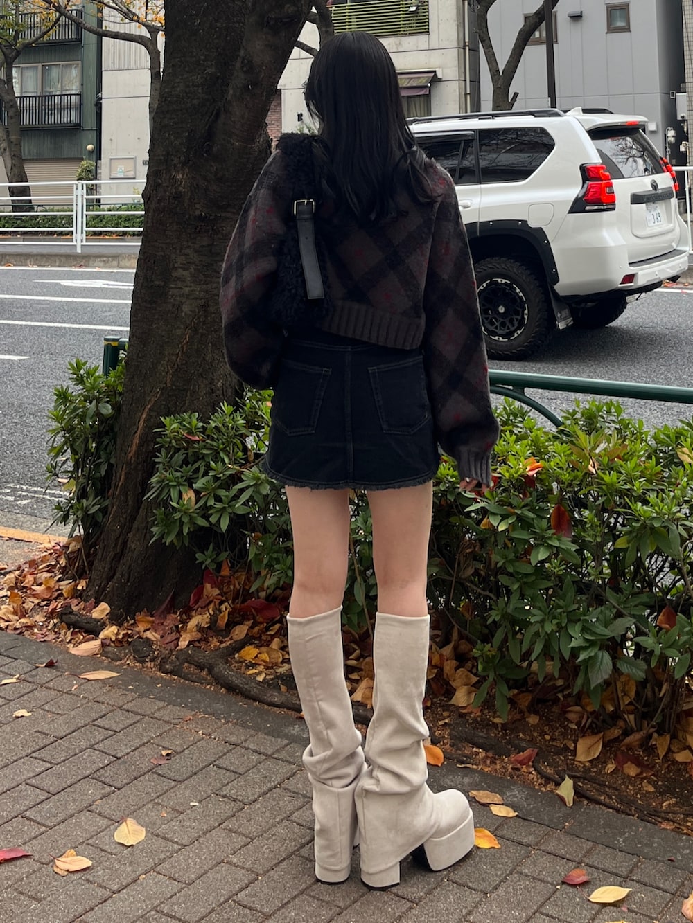 グレー系のニット/セーター、ブラック系のスカート、ホワイト系のブーツを着用したレディースの冬コーディネートの2枚目の写真