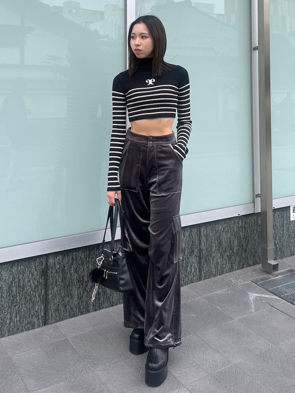 ブラック系のニット/セーター、ブラック系のブルゾン、グレー系のカーゴパンツを着用したレディースの秋コーディネートの4枚目の写真