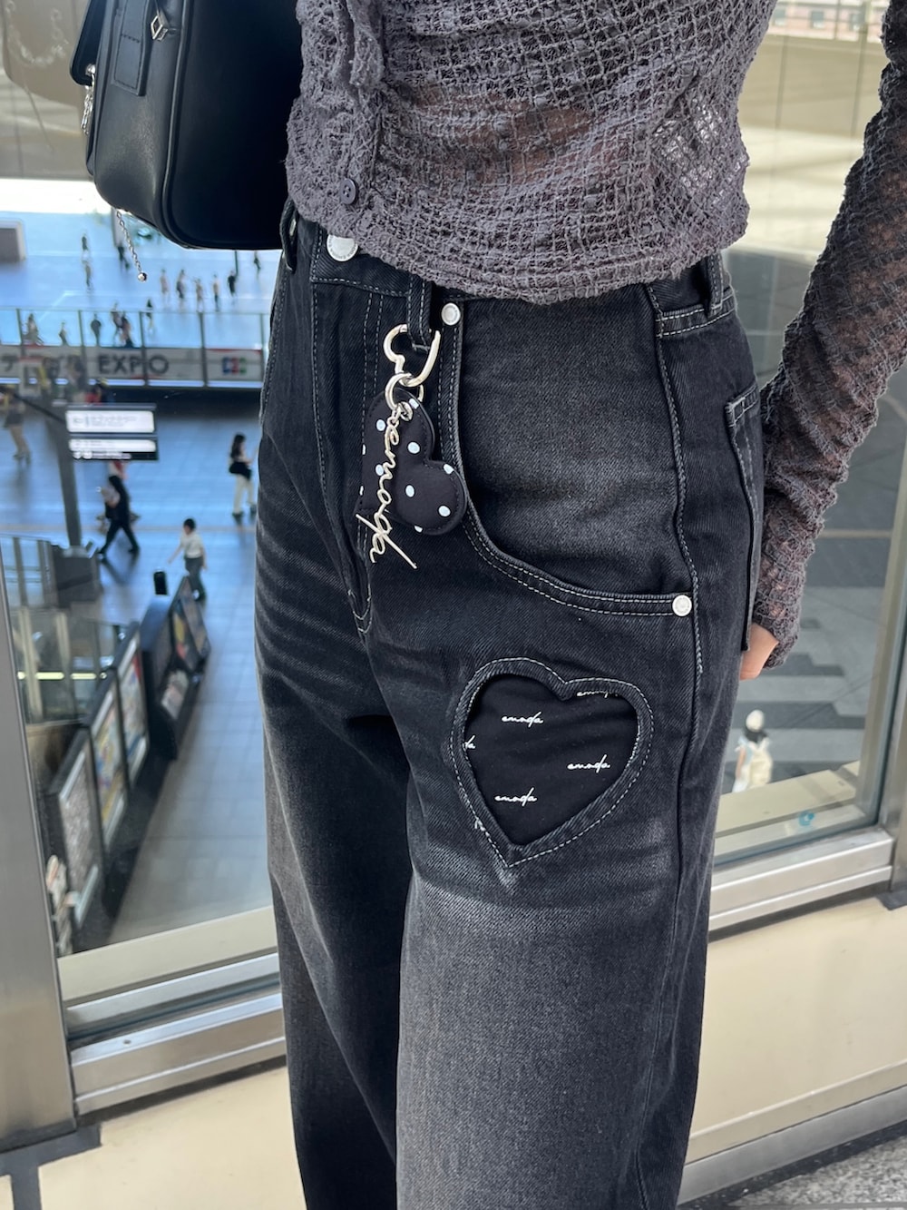 グレー系のTシャツ/カットソー、ブラック系のハンドバッグ、ブラック系のデニムパンツを着用したレディースの秋コーディネートの4枚目の写真