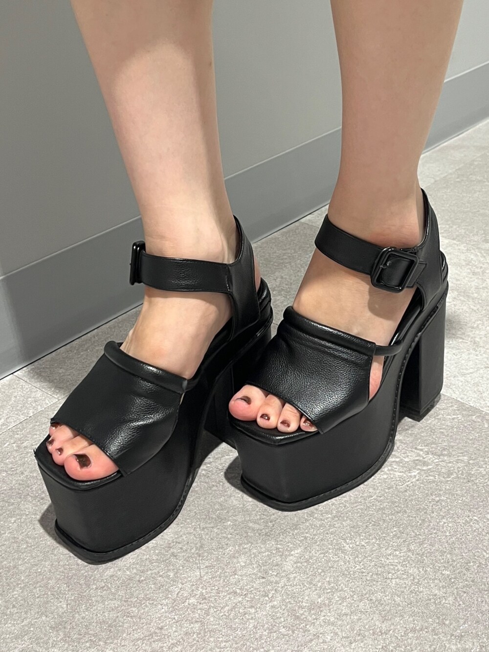 ブラック系のデニムパンツ、ブラック系のサンダル、ホワイト系のハンドバッグを着用したレディースの夏コーディネートの5枚目の写真