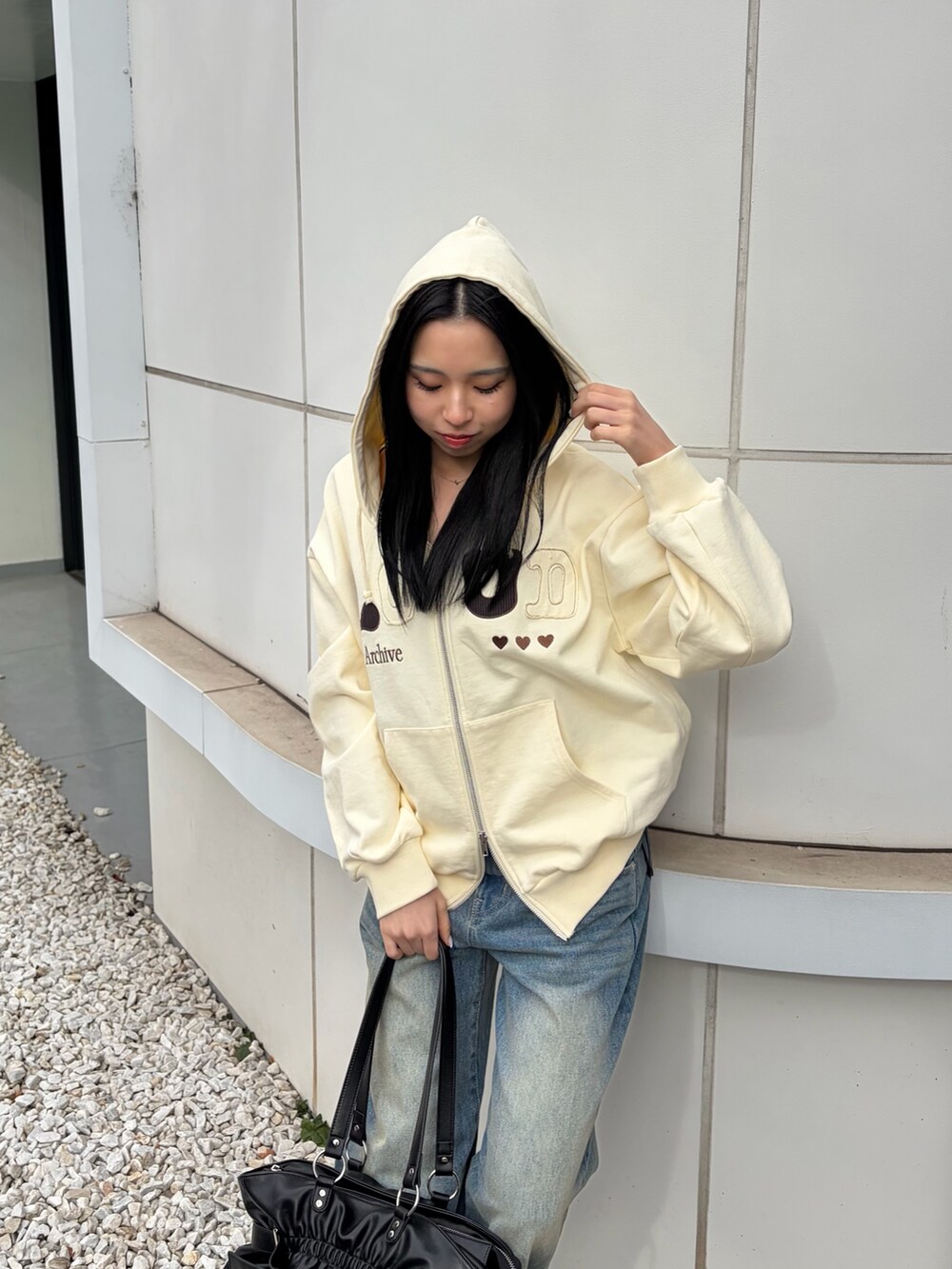 ホワイト系のパーカー、ブルー系のデニムパンツ、ブラック系のトートバッグを着用したレディースの冬コーディネートの4枚目の写真