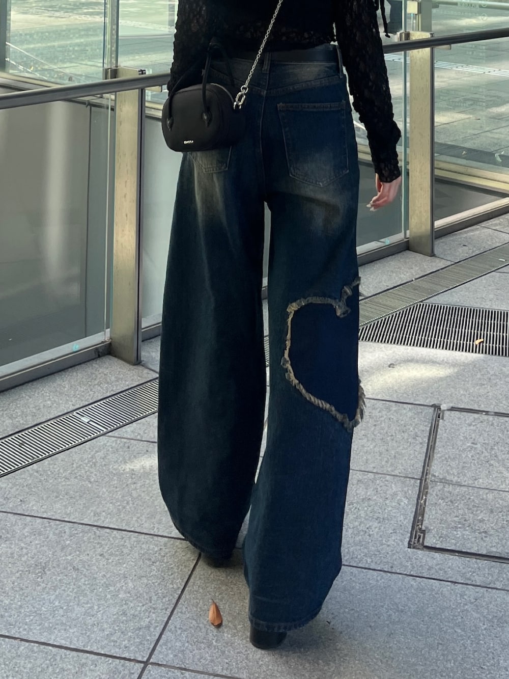 ブラック系のTシャツ/カットソー、ブルー系のデニムパンツ、ブラック系のブーツを着用したレディースの秋コーディネートの4枚目の写真