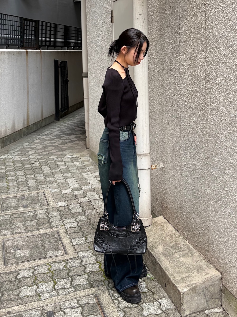 ブラック系のニット/セーター、ブルー系のデニムパンツ、ブラック系のショルダーバッグを着用したレディースの秋コーディネートの2枚目の写真