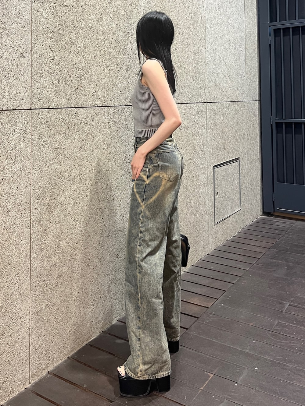 グレー系のタンクトップ、ブルー系のデニムパンツ、ブラック系のハンドバッグを着用したレディースの春コーディネートの2枚目の写真