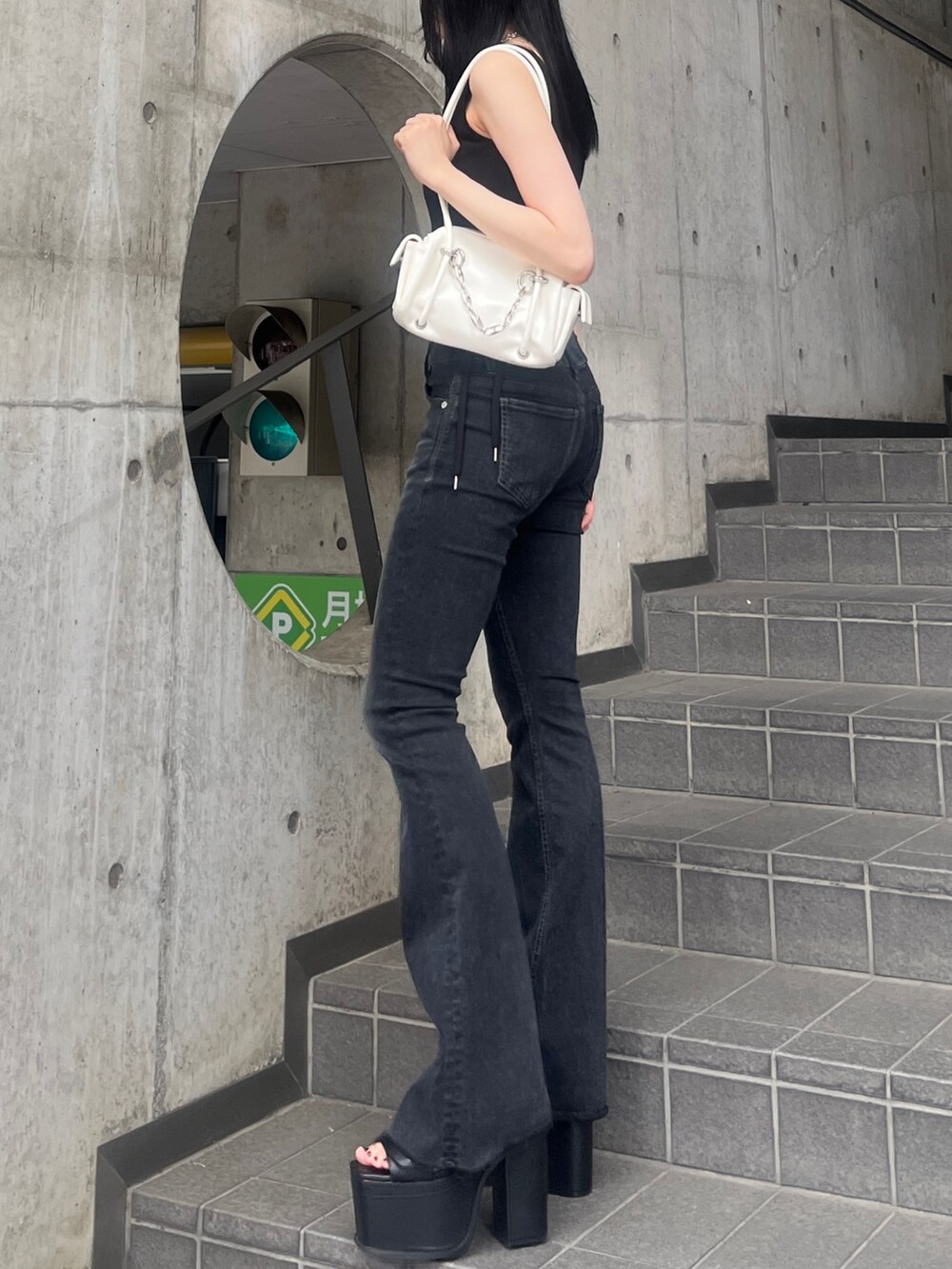 ブラック系のデニムパンツ、ブラック系のサンダル、ホワイト系のハンドバッグを着用したレディースの夏コーディネートの2枚目の写真