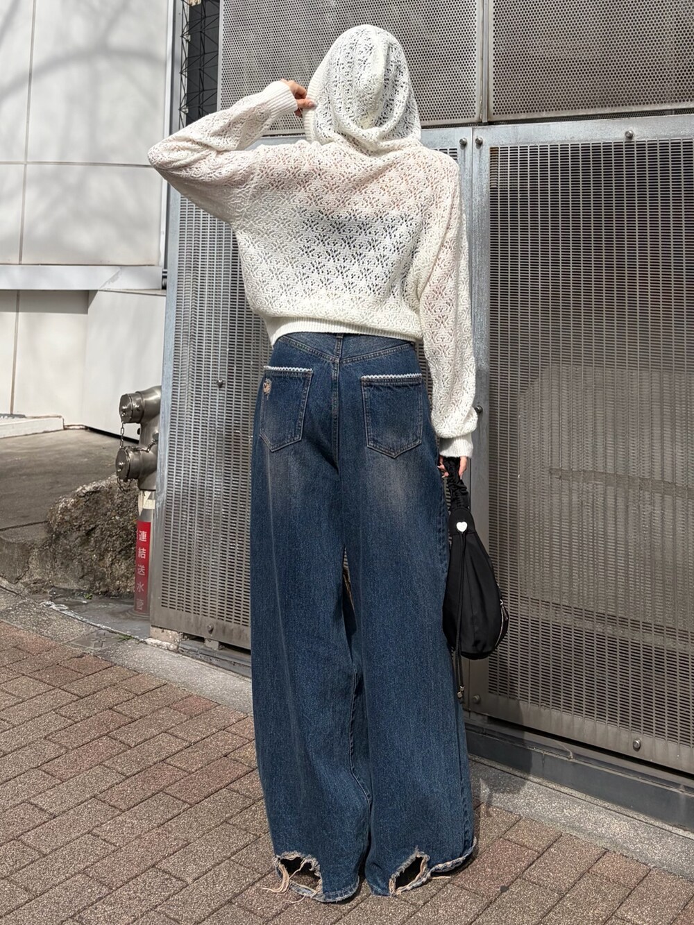 ホワイト系のパーカー、ブルー系のデニムパンツ、ブラック系のサンダルを着用したレディースの春コーディネートの3枚目の写真