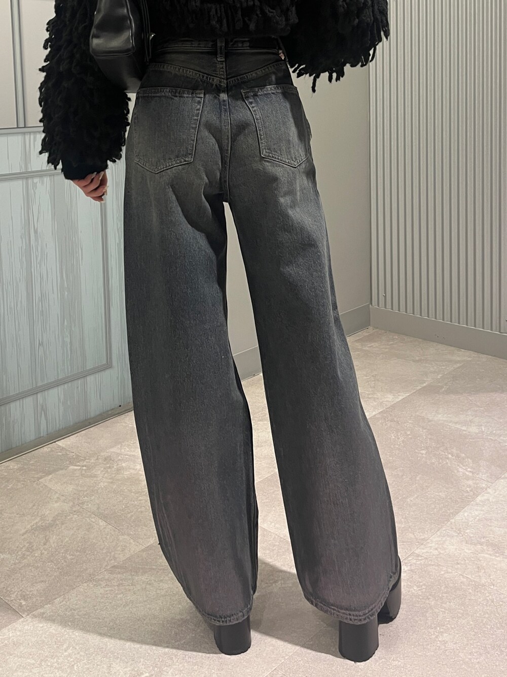 ブルー系のデニムパンツ、ブラック系のニット/セーター、ブラック系のショルダーバッグを着用したレディースの秋コーディネートの6枚目の写真