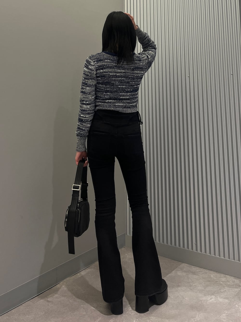 ブルー系のニット/セーター、ブラック系のデニムパンツ、ブラック系のショルダーバッグを着用したレディースの冬コーディネートの3枚目の写真