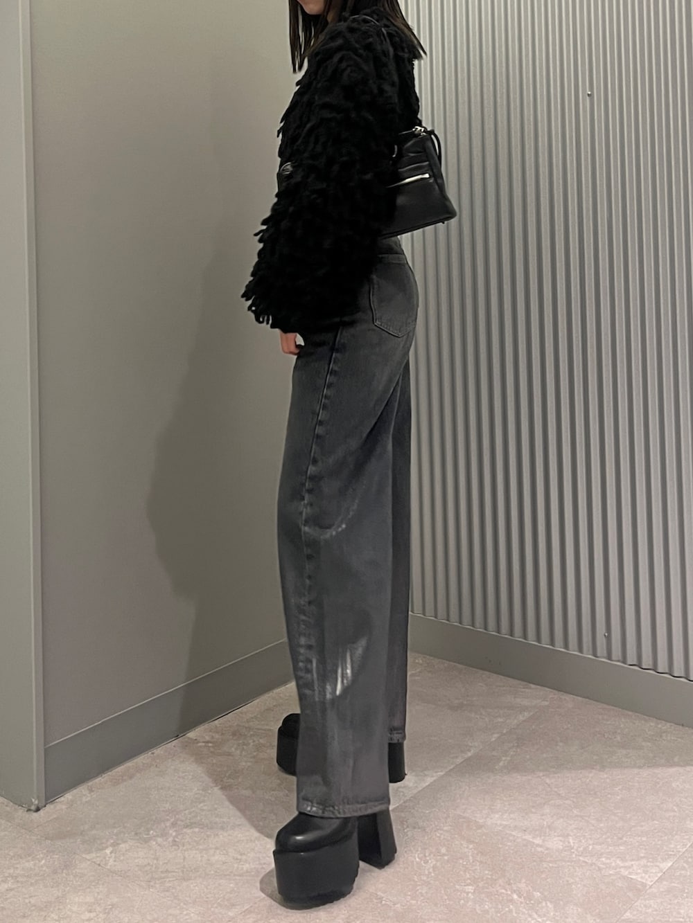 ブルー系のデニムパンツ、ブラック系のニット/セーター、ブラック系のショルダーバッグを着用したレディースの秋コーディネートの2枚目の写真