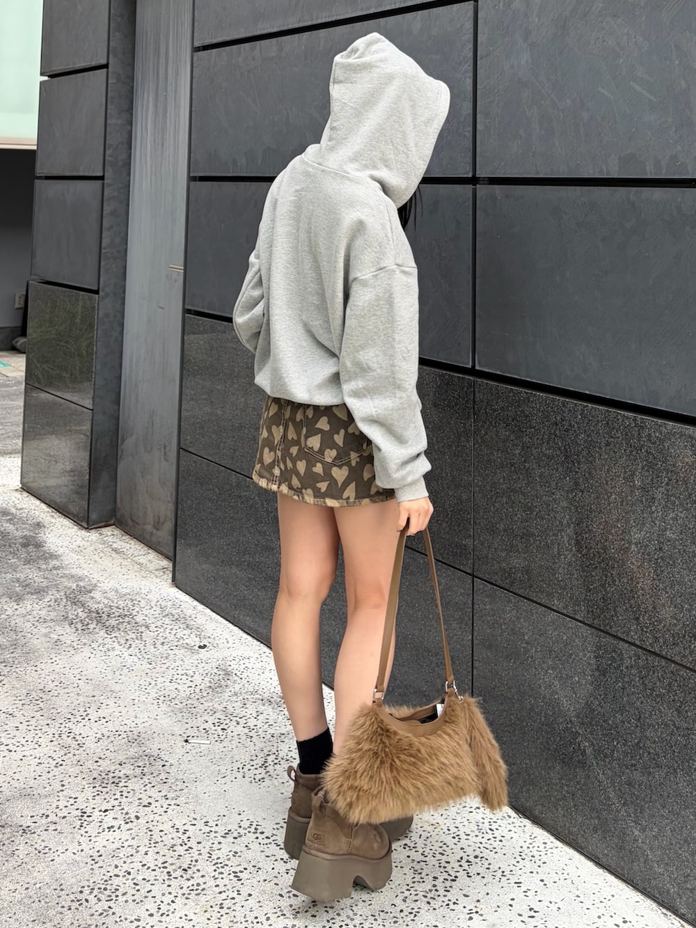 グレー系のパーカー、ベージュ系のスカート、ベージュ系のショルダーバッグを着用したレディースの冬コーディネートの2枚目の写真